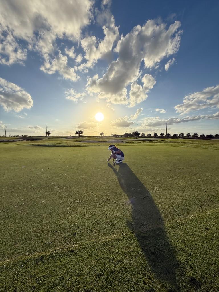 Alex lining up a putt at sunset