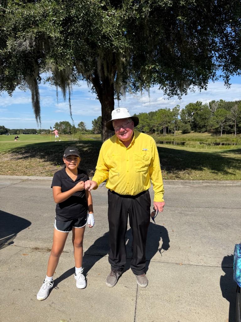Alex fist-bumping her coach on the golf course path